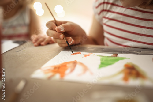 Children paint with brushes watercolors at table