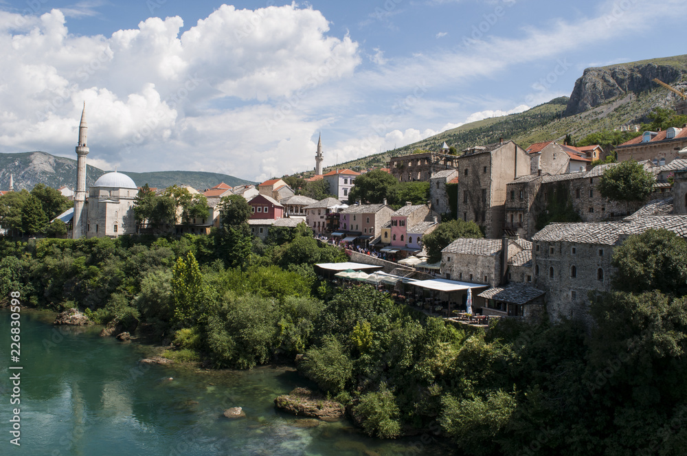 Bosnia: lo skyline di Mostar, la città che prende il nome dai guardiani del ponte (mostari) che nel medioevo custodivano lo Stari Most (Ponte Vecchio), visto dalle acque verdi del fiume Narenta