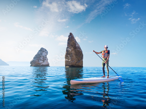 Stand up paddle boarding. Young man floating on a SUP board. The adventure of the sea with blue water on a surfing.