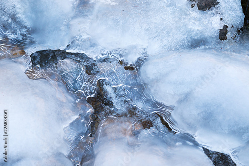 Surface of a frozen winter brook covered with ice.. photo