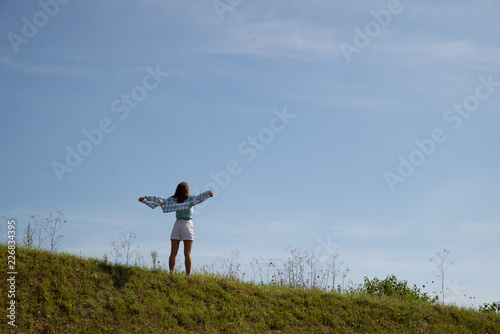 woman standing on top of the hill in warm sunny day