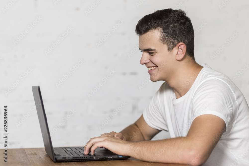 A young man sitting at a table and working on a laptop. A young man sitting at a table and working on a laptop.