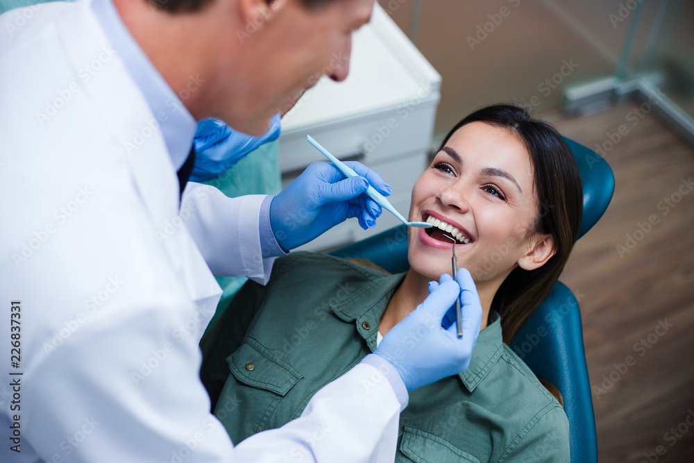 Amazing smile! Top view of dentist examining his beautiful patient in dentist’s office Amazing smile! Top view of dentist examining his beautiful patient in dentist’s office