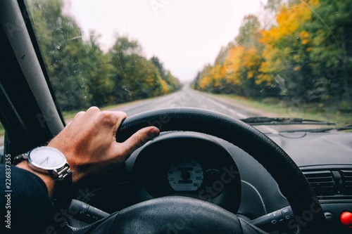 business driver driving a car on a forest autumn road. late, hurry, hours.