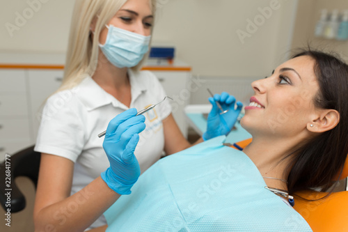 Pretty girl having mouth checkup in hospital by professional female dentist