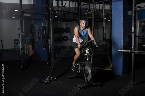 Sportsman riding stationary bicycle in gym