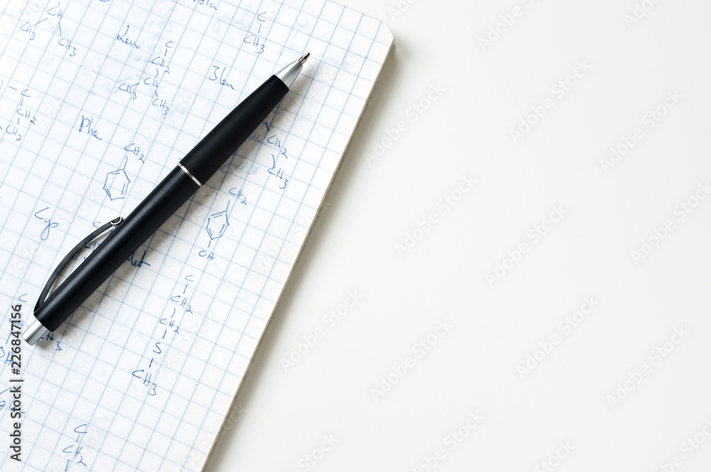 Notebook with chemical formulas and ballpoint pen on white table. Notebook with chemical formulas and ballpoint pen on white table.