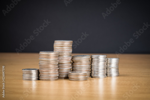 STACKED US MONEY COINS ON WOODEN SURFACE WITH BLACK BACKGROUND (COPY SPACE)