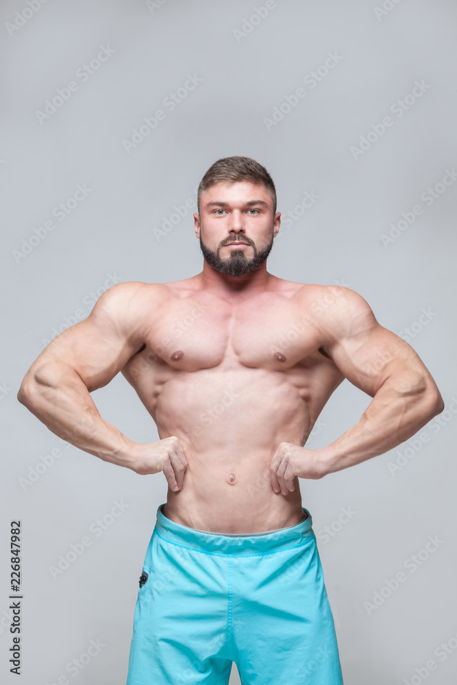 Strong Athletic Man Fitness Model Torso showing six pack abs. isolated on grey background with copyspace Strong Athletic Man Fitness Model Torso showing six pack abs. isolated on grey background with copyspace