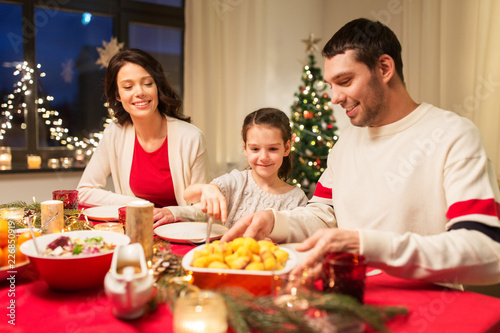 holidays  family and celebration concept - happy mother  father and little daughter having christmas dinner at home