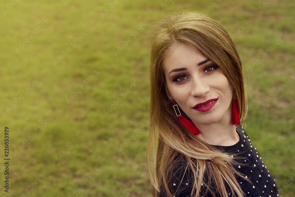 Fototapeta premium Portrait of a beautiful fashion young women smiling, with red lips, in park, Copy space.