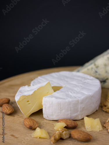 Variation of cheese, nuts and grapes on a wooden platter