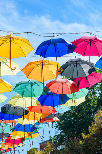 Different colorful umbrellas hanging over the street against sky