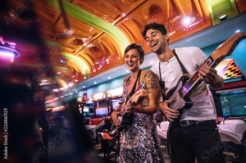 Smiling man and woman playing the guitar game at a gaming arcade