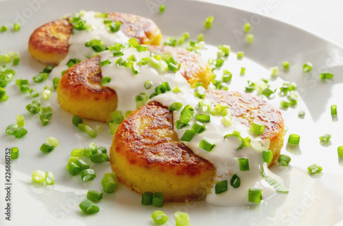 fried potato patties with sour cream decorated with onion