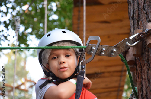 Portrait of cute little boy and girl walk on a rope bridge in an adventure rope park. © Dilya