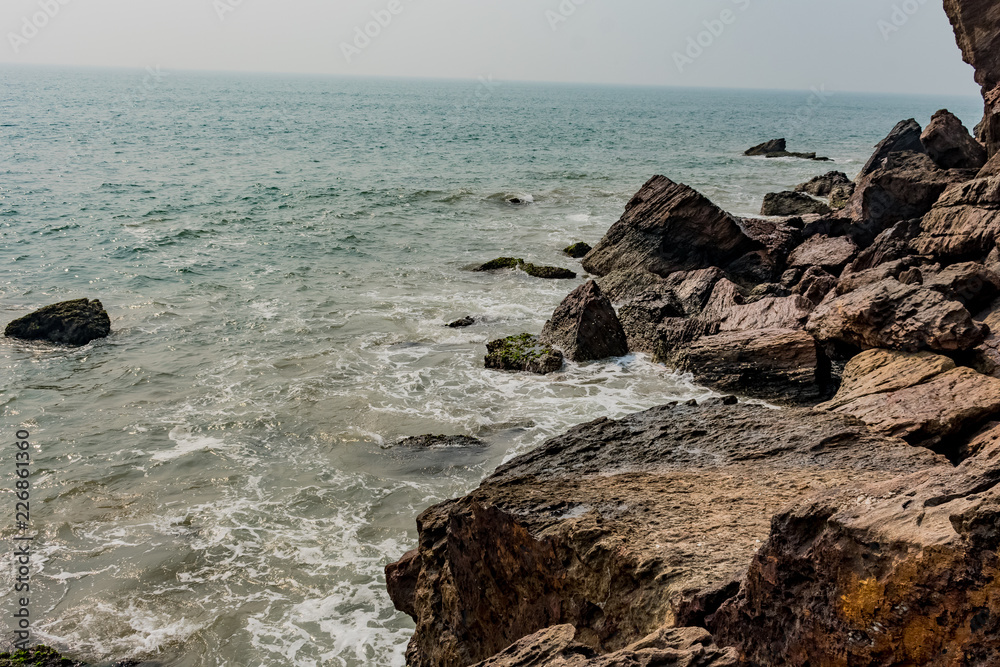 Yarada beach with indian ocean waves crashing onto the shore rocks and stones. Long exposure shot with silky smooth water and rock in the background. Yarada beach with indian ocean waves crashing onto the shore rocks and stones. Long exposure shot with silky smooth water and rock in the background.