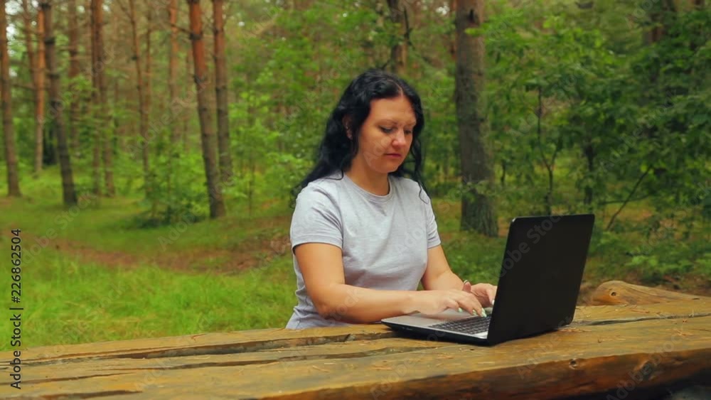 young woman in a park is typing on a laptop young woman in a park is typing on a laptop