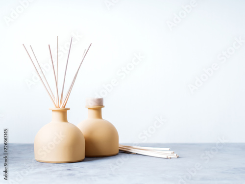 aroma reed diffuser home fragrance with rattan sticks on a light background with palm leaves and shadows.