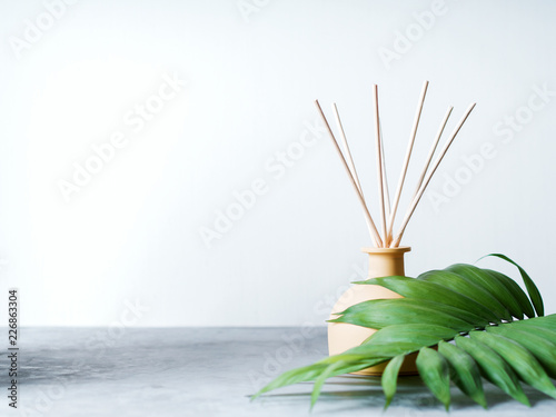 aroma reed diffuser home fragrance with rattan sticks on a light background with palm leaves and shadows. photo