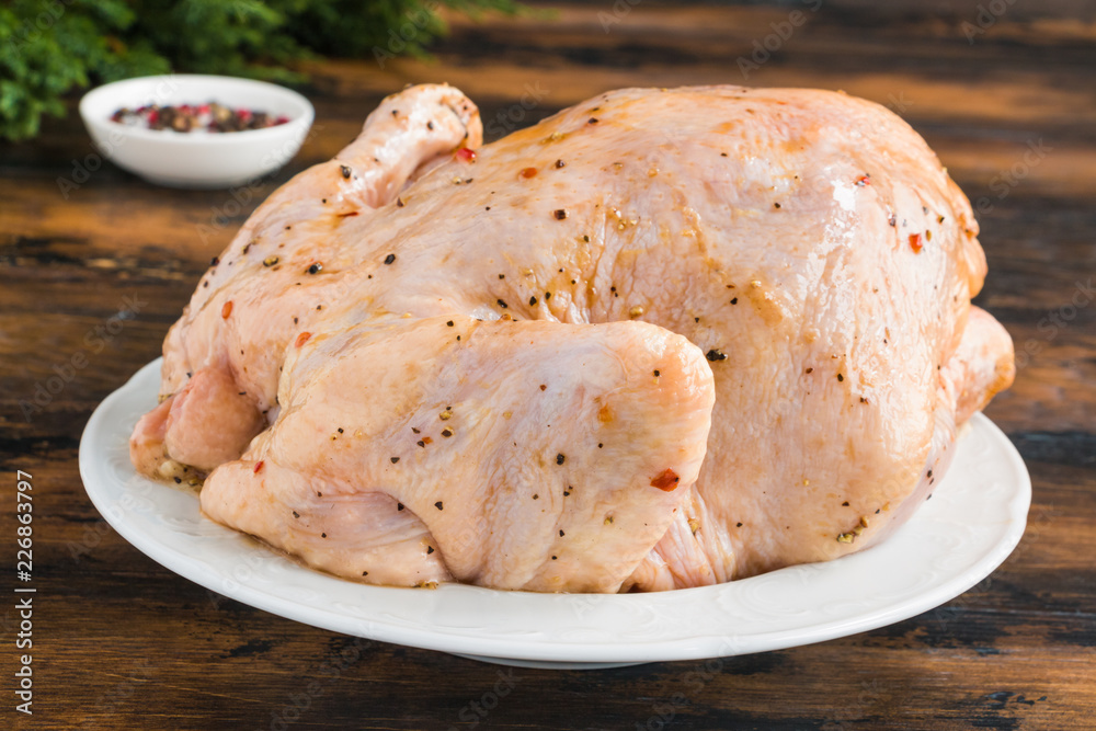 Uncooked whole chicken marinated with spices on white plate Uncooked whole chicken marinated with spices on white plate