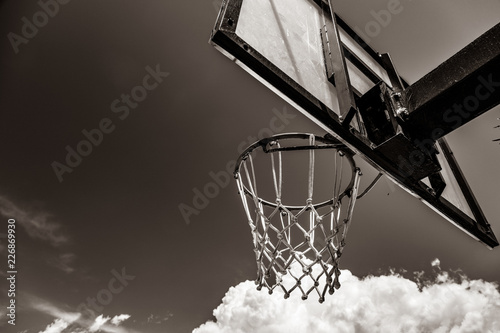 photo of the basketball hoop with clouds on background. Image in black and white color style