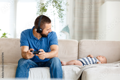 Young fahter playing video game during paternity leave photo