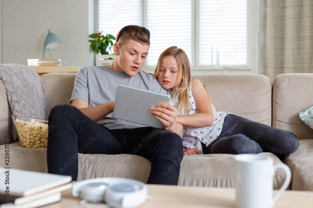 Siblings using a digital tablet together at home Siblings using a digital tablet together at home