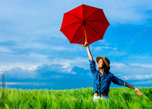 portrait of young beautiful woman with red umbrella in the field
