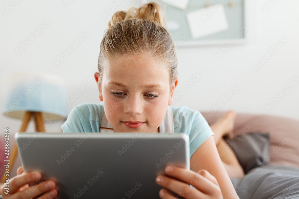 Cute girl using digital tablet in her bedroom Cute girl using digital tablet in her bedroom