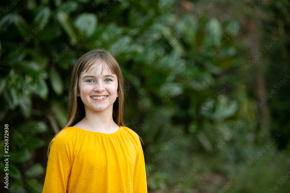 Smiling Tween Girl in Yellow Gold Outside in Greenery Smiling Tween Girl in Yellow Gold Outside in Greenery