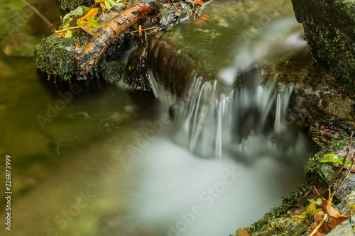 Nature waterfall at mountain river cascade. Colorful green mossy rocks  waterfall and cascade. Nature background.