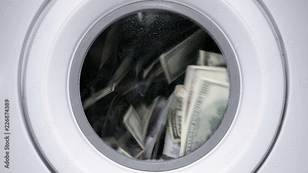 in a drum of a washing machine, money and dollars are spinning and laundered, close-up in a drum of a washing machine, money and dollars are spinning and laundered, close-up