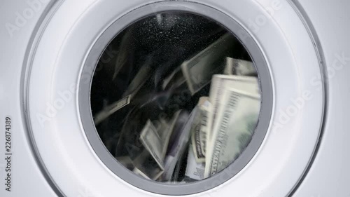 in a drum of a washing machine, money and dollars are spinning and laundered, close-up photo