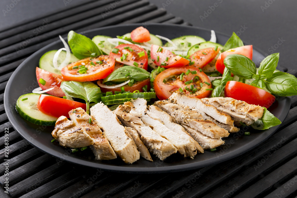 Vegetable salad and grilled chicken on a black background. Healthy food. Diet.