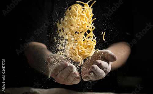 Fotografia close hand make pasta toss on a black background before cooking the dish