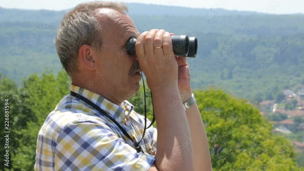Male tourist looking through binoculars Male tourist looking through binoculars