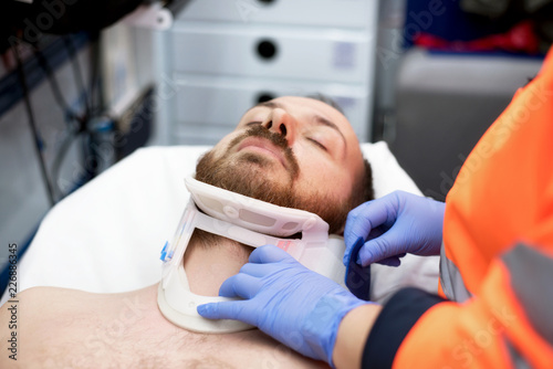 Emergency doctor putting a cervical collar to a patient in the ambulance photo