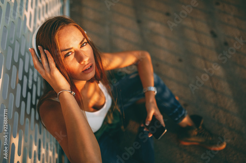 Young woman listening to music via headphones and smartphone outdoor