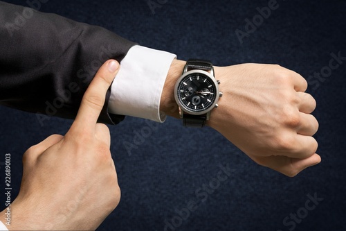Businessman pointing at hand watch on white