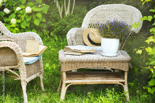 Wicker table, chairs and books in the garden at summer time