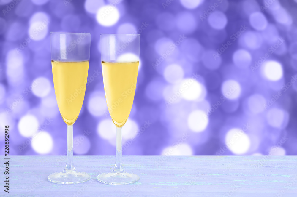 Two glasses with champagne on a wooden blue background. Blurred background, bokeh.