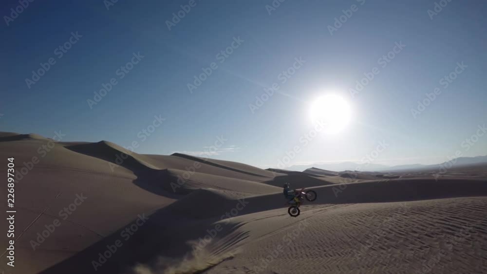 Aerial, motocross biker jumps off dunes in Mojave desert