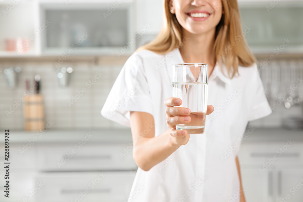 Young woman holding glass with clean water in kitchen, closeup Young woman holding glass with clean water in kitchen, closeup