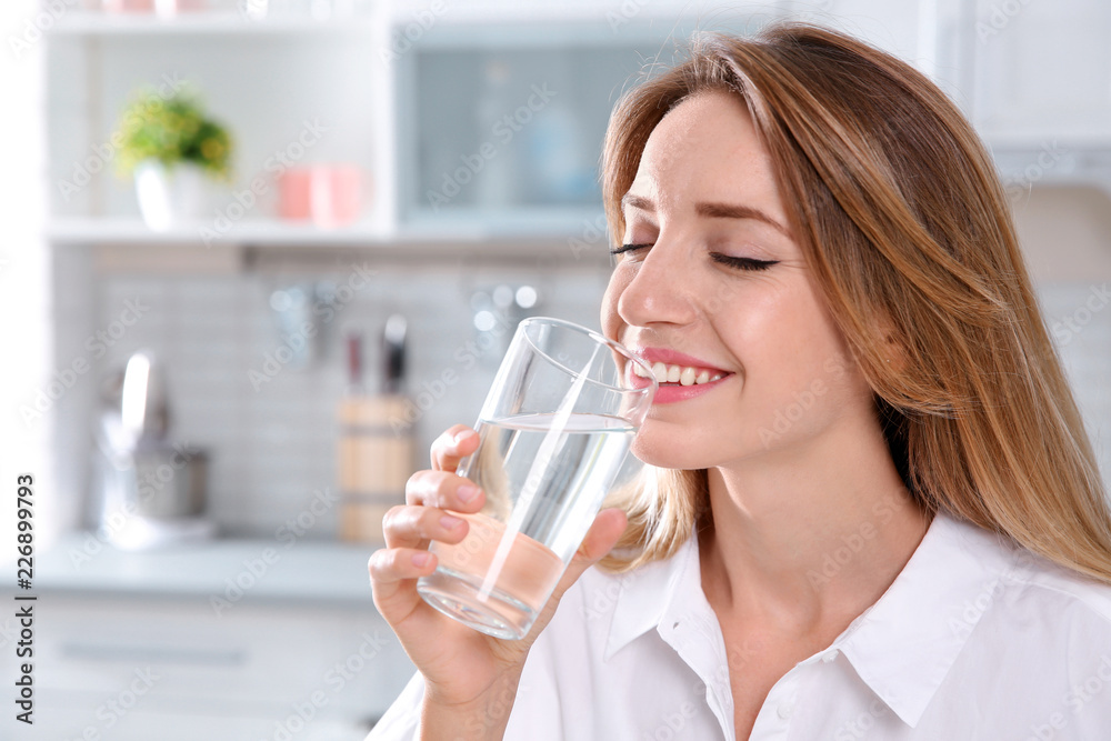Young woman drinking clean water from glass in kitchen Young woman drinking clean water from glass in kitchen