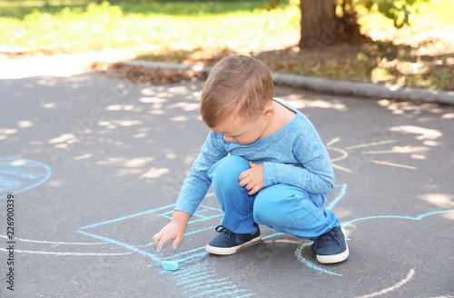 Little child drawing with colorful chalk on asphalt © New Africa