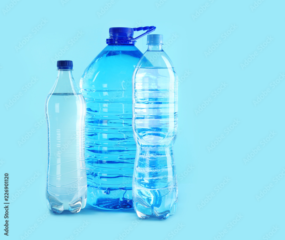 Different plastic bottles with pure water on color background. Space for text Different plastic bottles with pure water on color background. Space for text