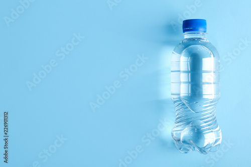 Bottle of water on color background, top view. Space for text