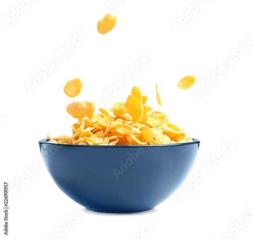 Crispy cornflakes falling into bowl on white background