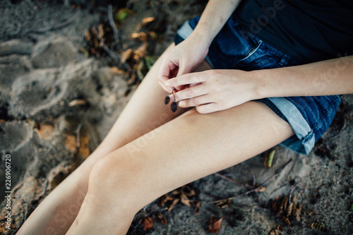 Legs of a girl in shorts sitting on a sandy beach